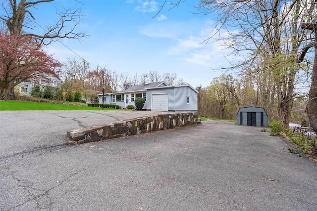 view of front of property with driveway, an outbuilding, an attached garage, and a storage shed