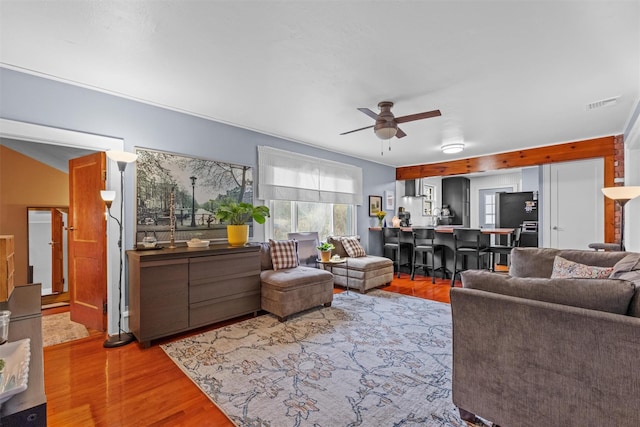 living area with ceiling fan, visible vents, and wood finished floors