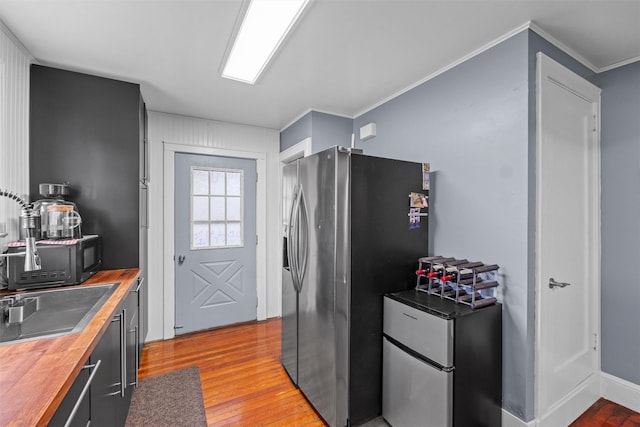 kitchen with light wood-style flooring, wooden counters, a sink, crown molding, and stainless steel refrigerator with ice dispenser