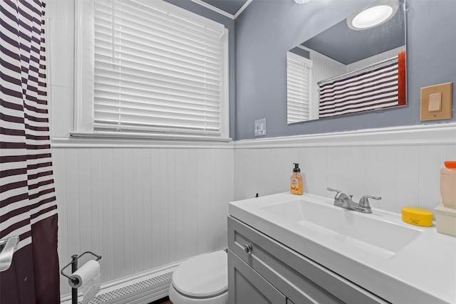 bathroom featuring a wainscoted wall, toilet, vanity, and a baseboard heating unit
