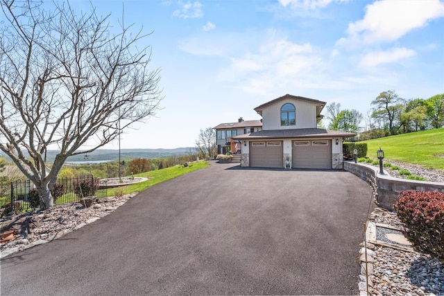 view of front of property featuring a garage, aphalt driveway, fence, a front yard, and stone siding