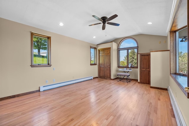 empty room featuring ceiling fan, a wealth of natural light, baseboard heating, and light wood finished floors