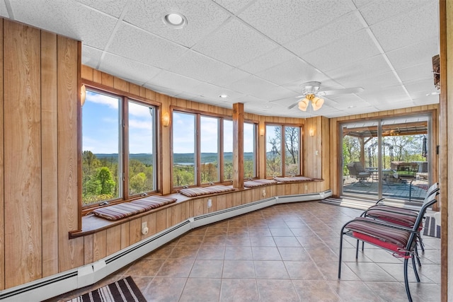unfurnished sunroom featuring tile patterned floors, wood walls, recessed lighting, a drop ceiling, and a baseboard heating unit