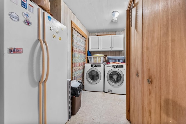 clothes washing area featuring cabinet space and washer and clothes dryer