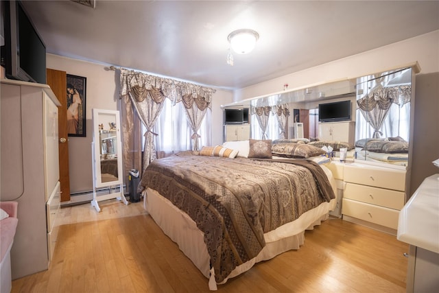 bedroom with light wood-style floors and a baseboard radiator