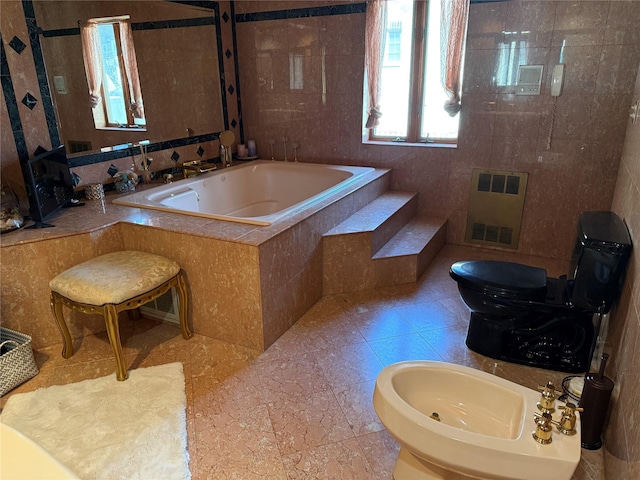 bathroom featuring a garden tub, a bidet, tile walls, tile patterned floors, and toilet
