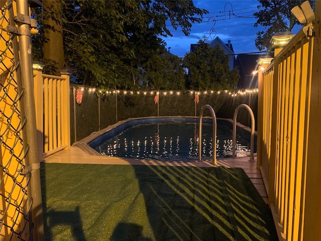 pool at twilight with a fenced backyard