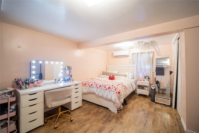 bedroom featuring wood finished floors and a wall unit AC
