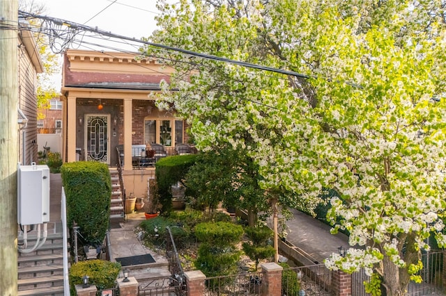 exterior space featuring fence, covered porch, and brick siding