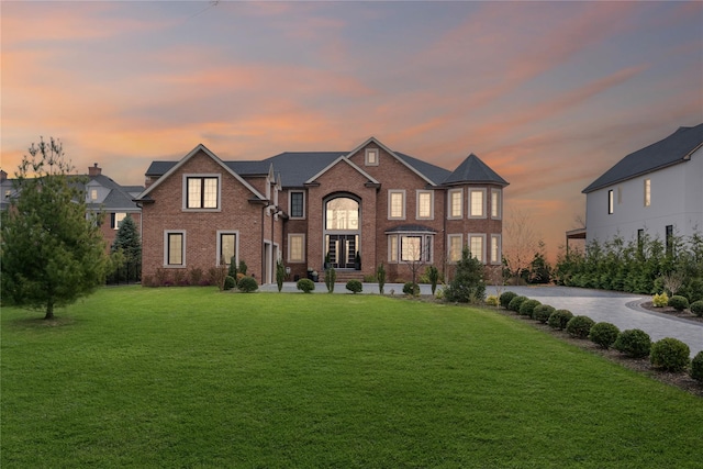 view of front of house with a yard and brick siding