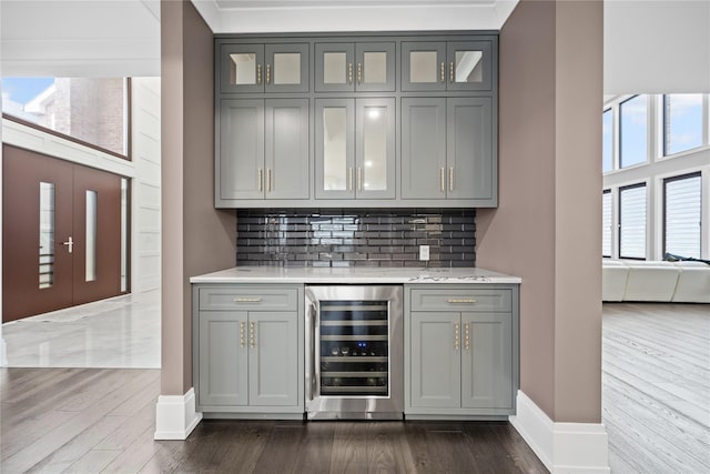 bar with decorative backsplash, wine cooler, baseboards, dark wood-style floors, and a dry bar