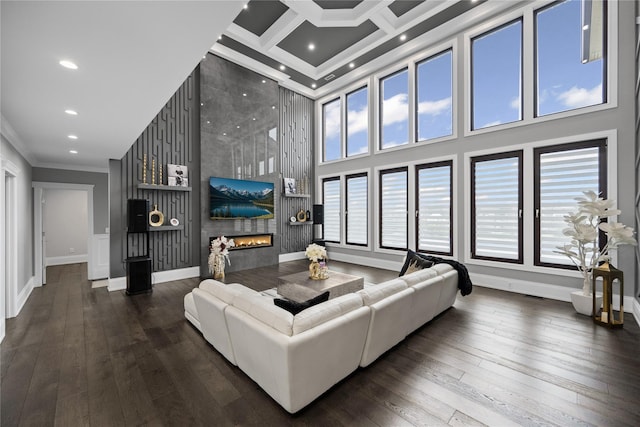 living room with crown molding, a fireplace, hardwood / wood-style flooring, and a towering ceiling