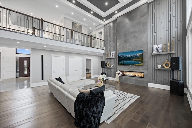living room featuring wood-type flooring, baseboards, a tile fireplace, and a towering ceiling