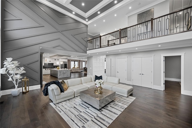 living area featuring baseboards, ornamental molding, wood finished floors, and a towering ceiling
