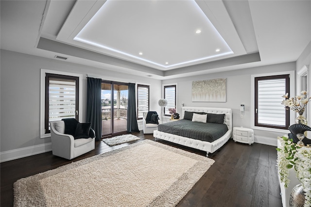 bedroom with access to exterior, baseboards, a tray ceiling, and visible vents