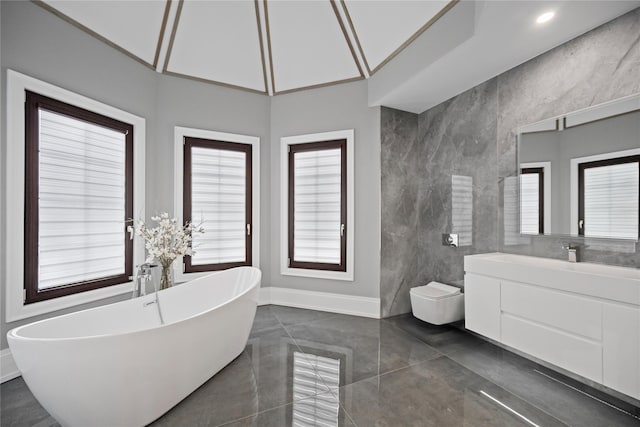 bathroom featuring baseboards, a freestanding bath, and vanity