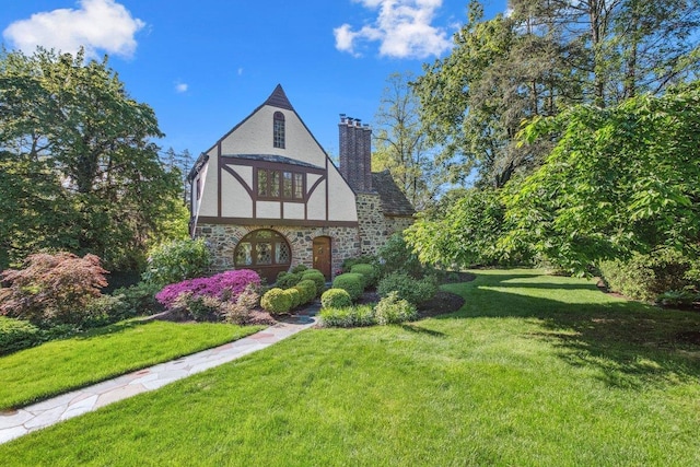 view of front of house featuring stone siding, stucco siding, a front lawn, and a chimney