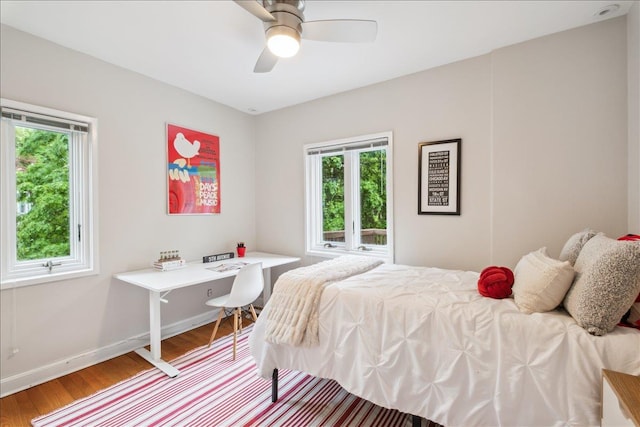 bedroom featuring multiple windows, wood finished floors, baseboards, and ceiling fan