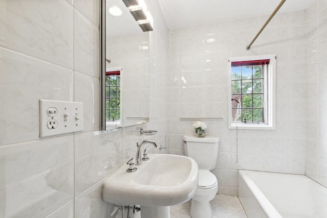 bathroom featuring tile walls, toilet, a tub to relax in, a sink, and a shower