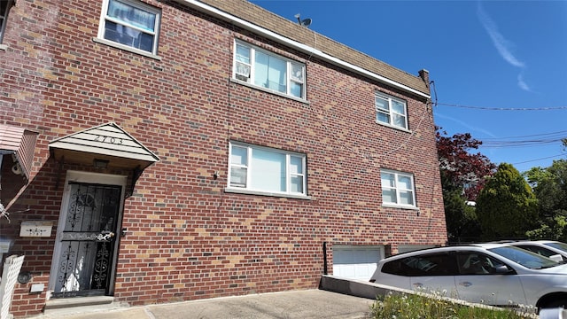 exterior space featuring an attached garage, aphalt driveway, and brick siding