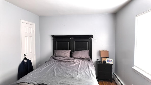 bedroom with baseboard heating and wood finished floors