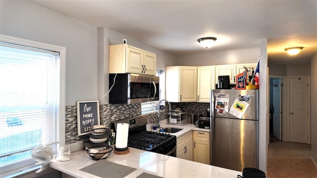 kitchen featuring appliances with stainless steel finishes, tasteful backsplash, a sink, tile patterned floors, and light stone counters