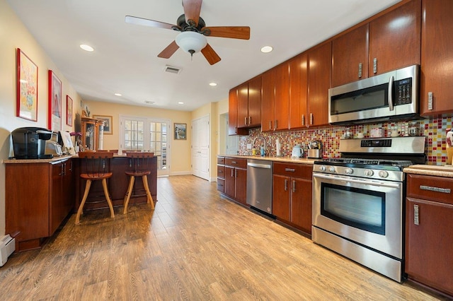 64 Harmon St, Long Beach, NY 11561 - kitchen featuring stainless steel appliances, light wood-type flooring, a kitchen bar, tasteful backsplash, and recessed lighting