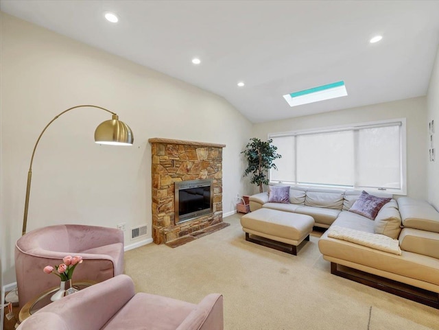 carpeted living area with a stone fireplace, visible vents, baseboards, lofted ceiling with skylight, and recessed lighting