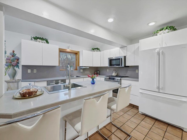 kitchen featuring light countertops, white cabinets, tasteful backsplash, a sink, and appliances with stainless steel finishes