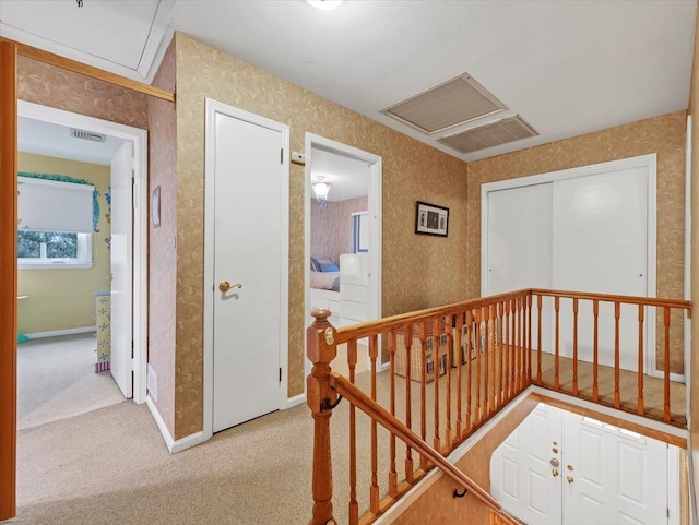 hall featuring carpet flooring, attic access, baseboards, an upstairs landing, and visible vents