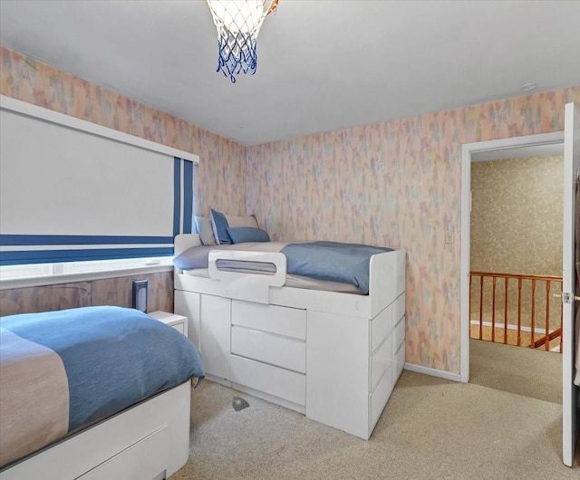 bedroom with wallpapered walls, light carpet, and baseboards