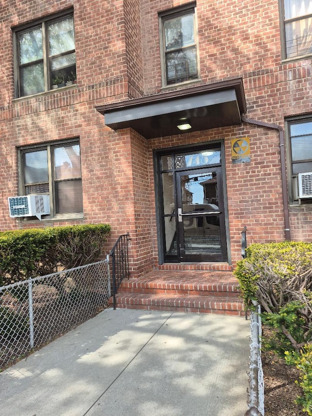property entrance featuring fence, cooling unit, and brick siding