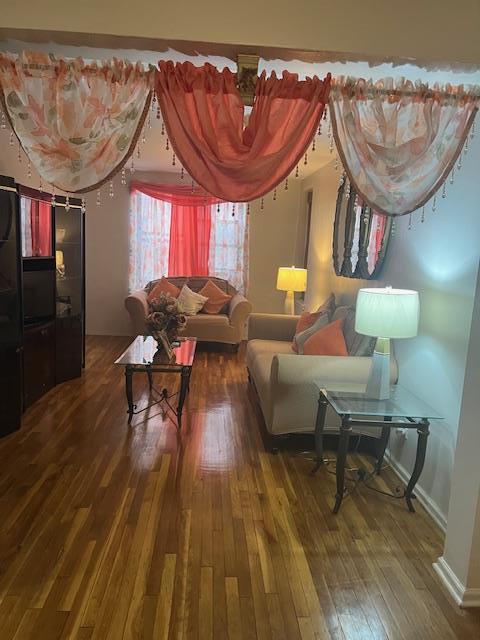 living area featuring baseboards and hardwood / wood-style floors