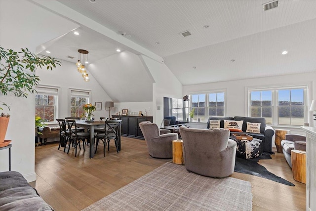 living area featuring lofted ceiling, wood finished floors, and visible vents
