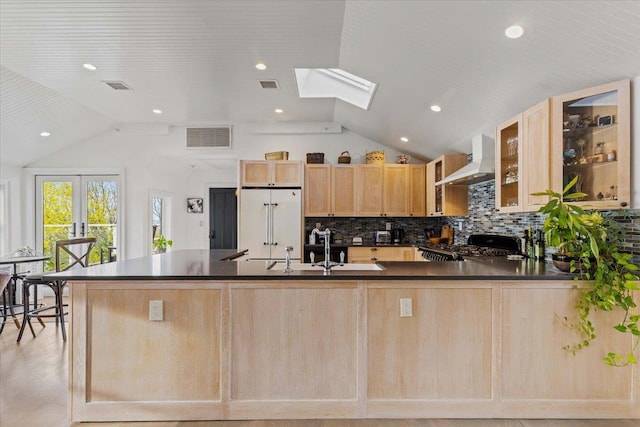 kitchen featuring visible vents, dark countertops, built in fridge, light brown cabinets, and wall chimney exhaust hood