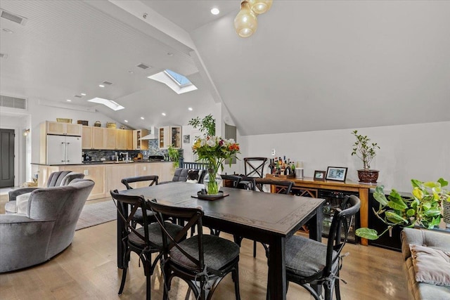 dining space featuring visible vents, recessed lighting, light wood-style floors, and vaulted ceiling with skylight