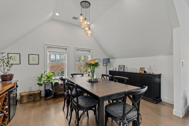 dining room featuring baseboards, visible vents, lofted ceiling, and light wood-style floors