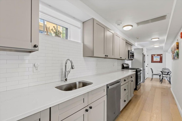 kitchen with a sink, gray cabinets, stainless steel appliances, and visible vents