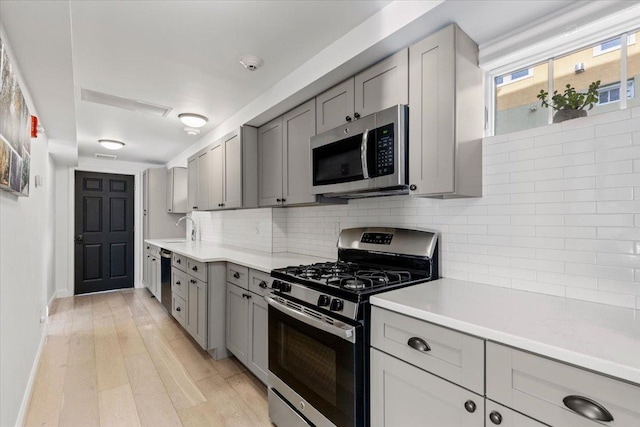 kitchen with gray cabinets, appliances with stainless steel finishes, and tasteful backsplash