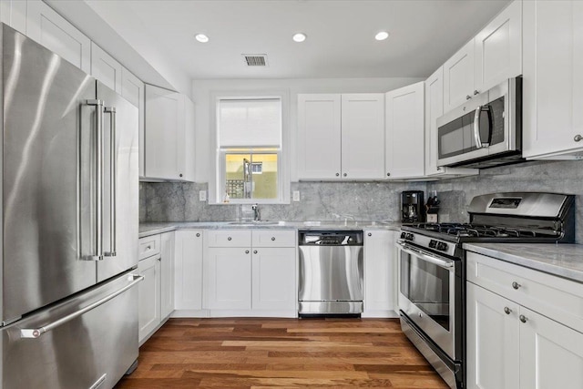 kitchen featuring a sink, stainless steel appliances, wood finished floors, and visible vents