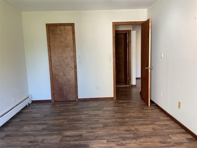 empty room with wood finished floors, baseboards, and a baseboard heating unit
