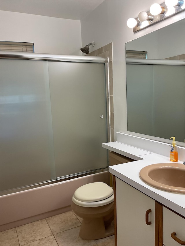 bathroom with vanity, bath / shower combo with glass door, tile patterned flooring, and toilet