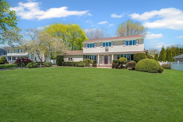 traditional-style house featuring a front lawn and fence