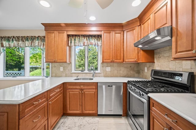 kitchen with light countertops, a sink, under cabinet range hood, and stainless steel appliances