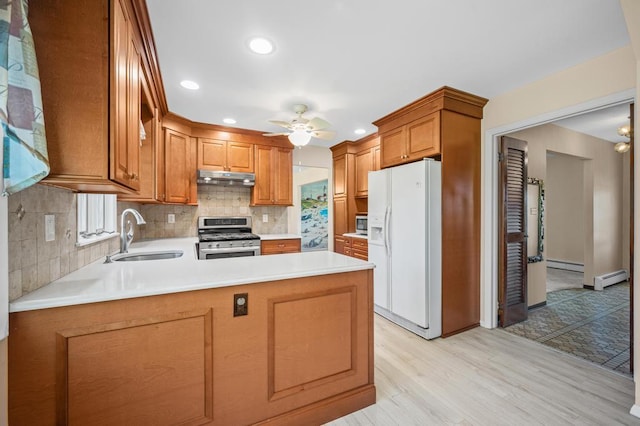 kitchen with a baseboard radiator, baseboard heating, under cabinet range hood, a sink, and stainless steel appliances