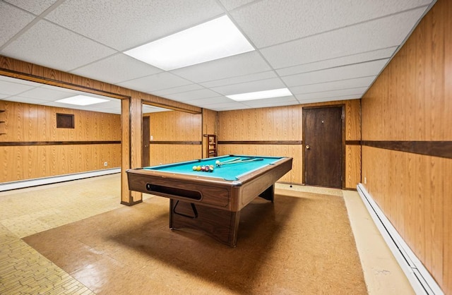 recreation room with baseboard heating, tile patterned floors, wood walls, a paneled ceiling, and a baseboard radiator