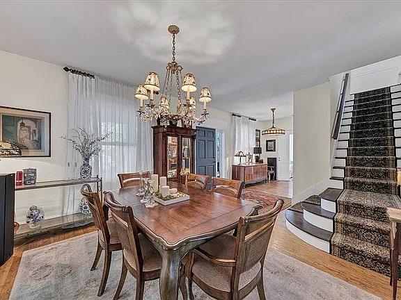 dining area with stairs, wood finished floors, a chandelier, and a healthy amount of sunlight