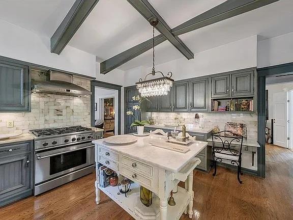 kitchen with open shelves, high end stainless steel range, beamed ceiling, light countertops, and backsplash