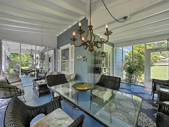 sunroom / solarium with an inviting chandelier and beam ceiling