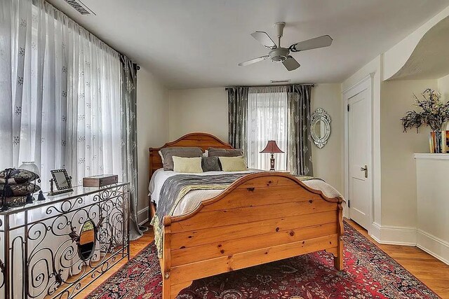 bedroom featuring ceiling fan, baseboards, visible vents, and wood finished floors